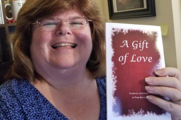 Annette Teepe holding up a copy of A Gift of Love