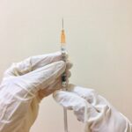 person's gloved hands holding a syringe