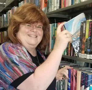 Annette Teepe tilting Memphis Mosaic book back on library shelf. 